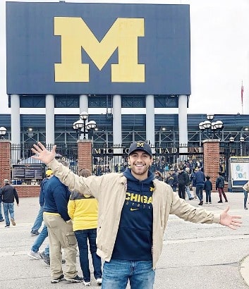 Jason wearing blond jacket with black hoodie inside. 